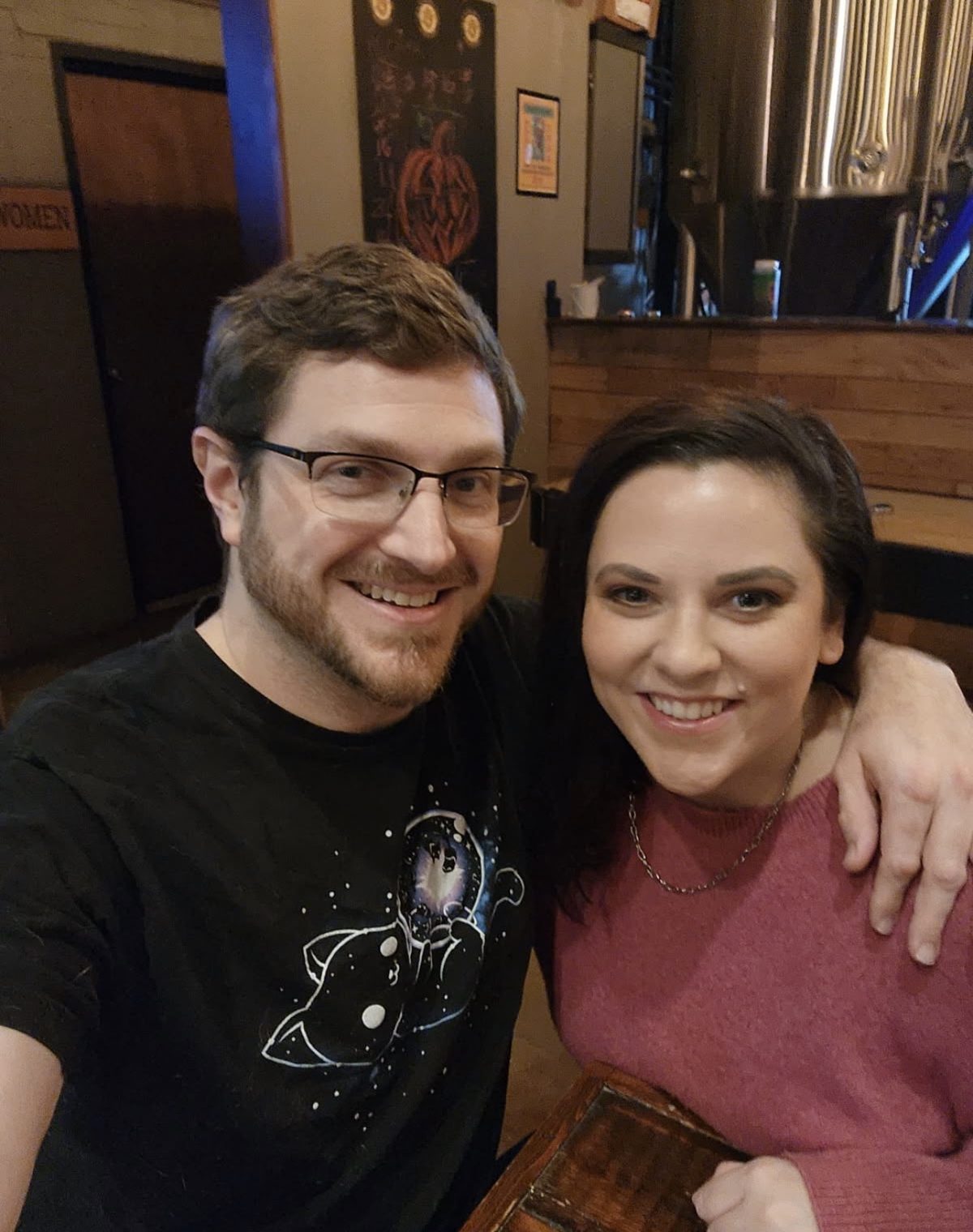 Erin and Andrew at Alvarium Beer Co. in New Britain, brewing tanks behind them.