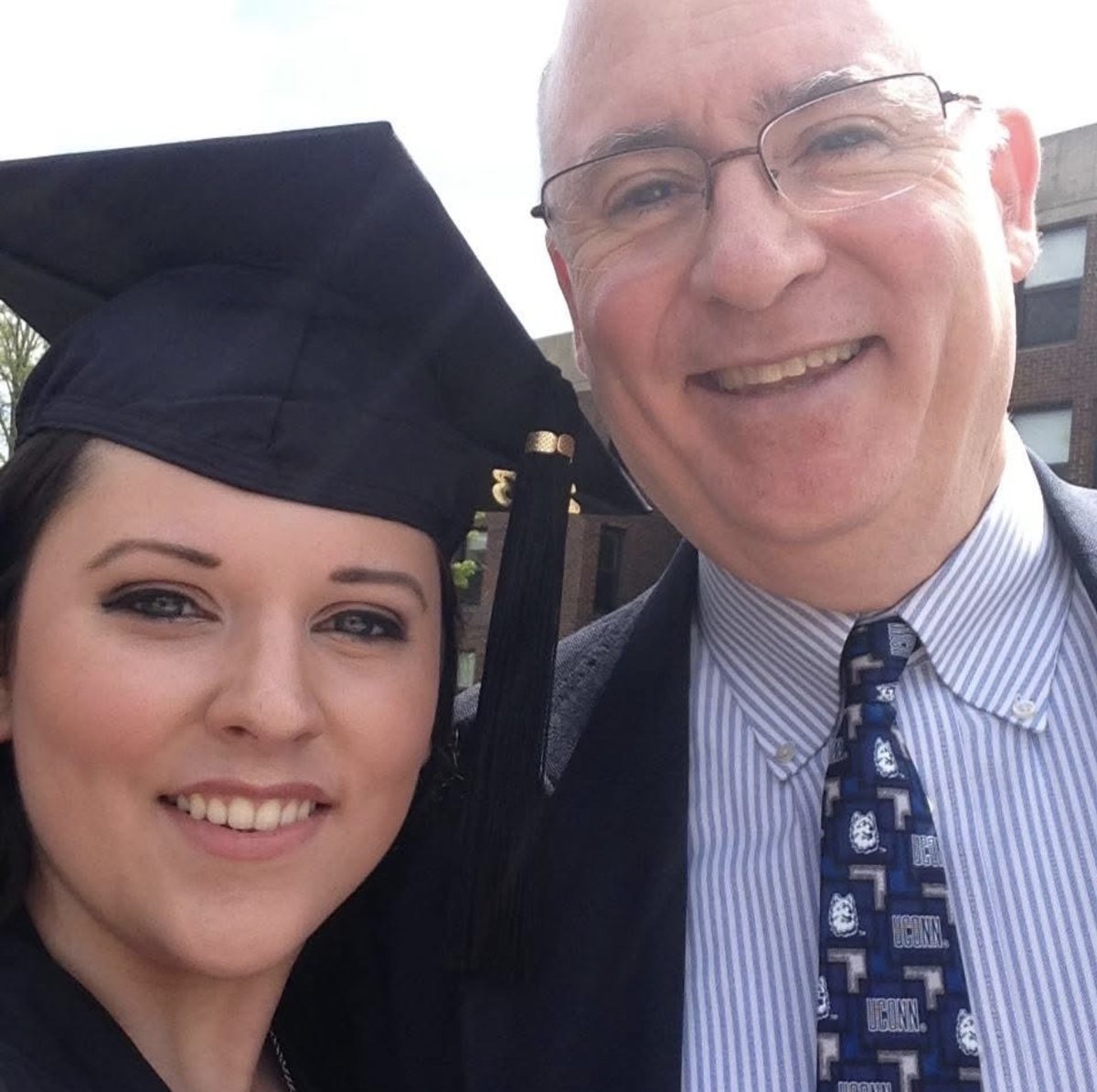 Erin in cap and gown at her 2013 UConn graduation with her father, who is wearing a UConn Huskies tie.